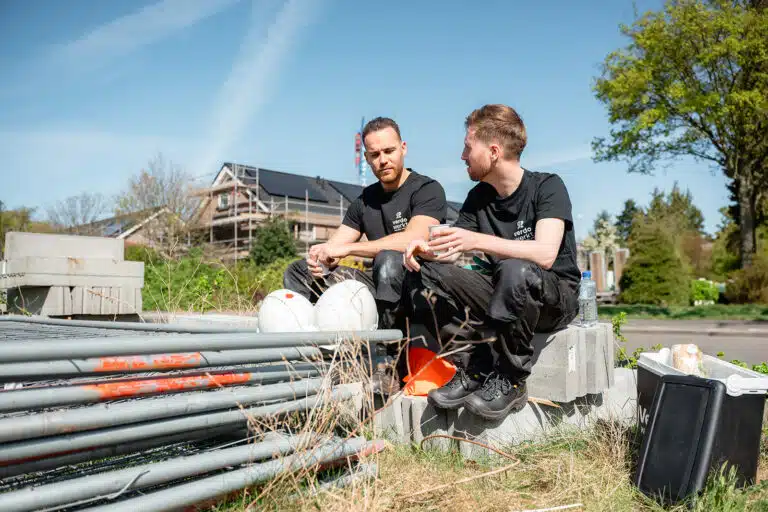 Twee medewerkers van Verdo Werkt in gesprek naast bouwmaterialen